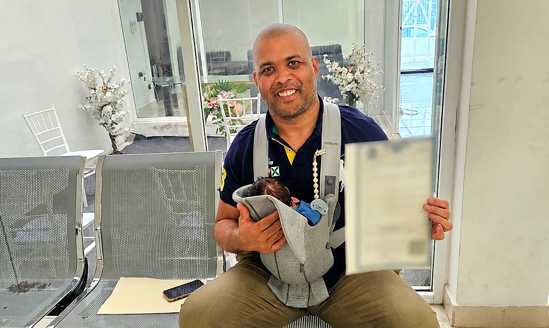 Will S., single father, holding his newborn and the Amparo birth certificate — Fertility Solutions Center
